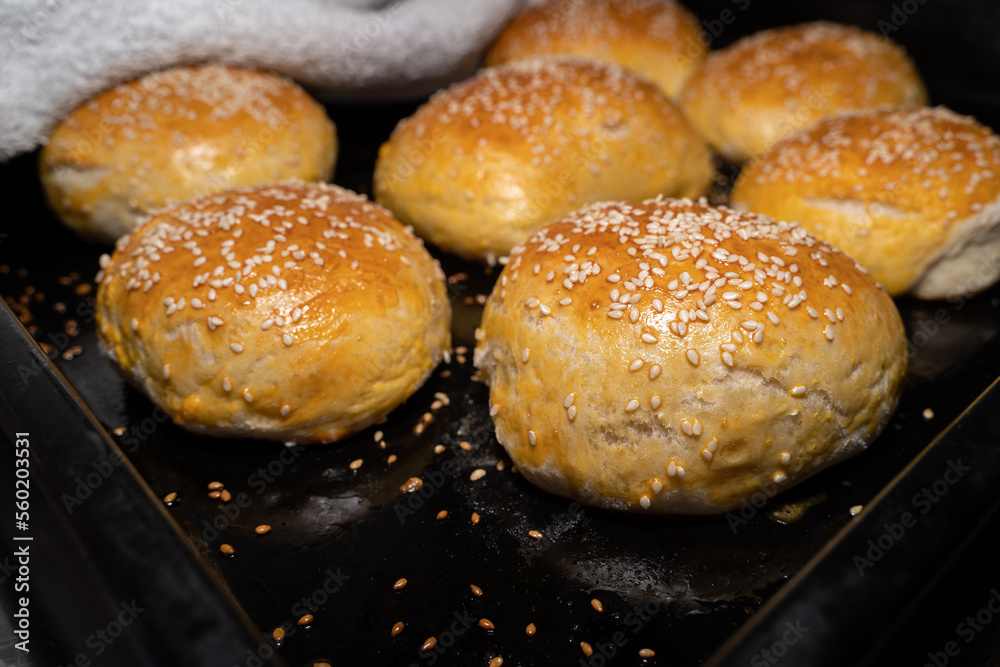 Freshly baked homemade buns with sesame seeds on a baking sheet