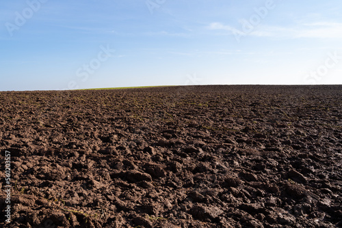 Plowed agricultural hill on a sunny day with blue sky in spring photo