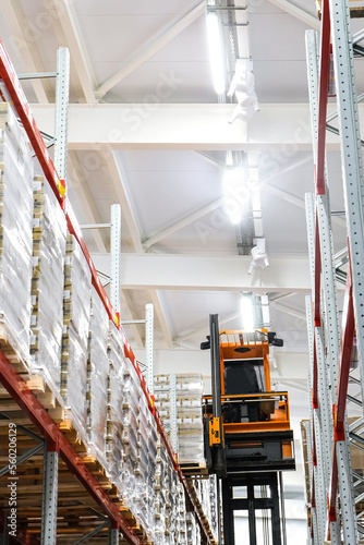 Narrow aisle high-rise stacker. Reach truck with raised cab. High height stacker loader in a industrial warehouse building with rows of racks. photo
