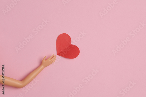 Doll hand with a heart on a pink background. Love concept photo