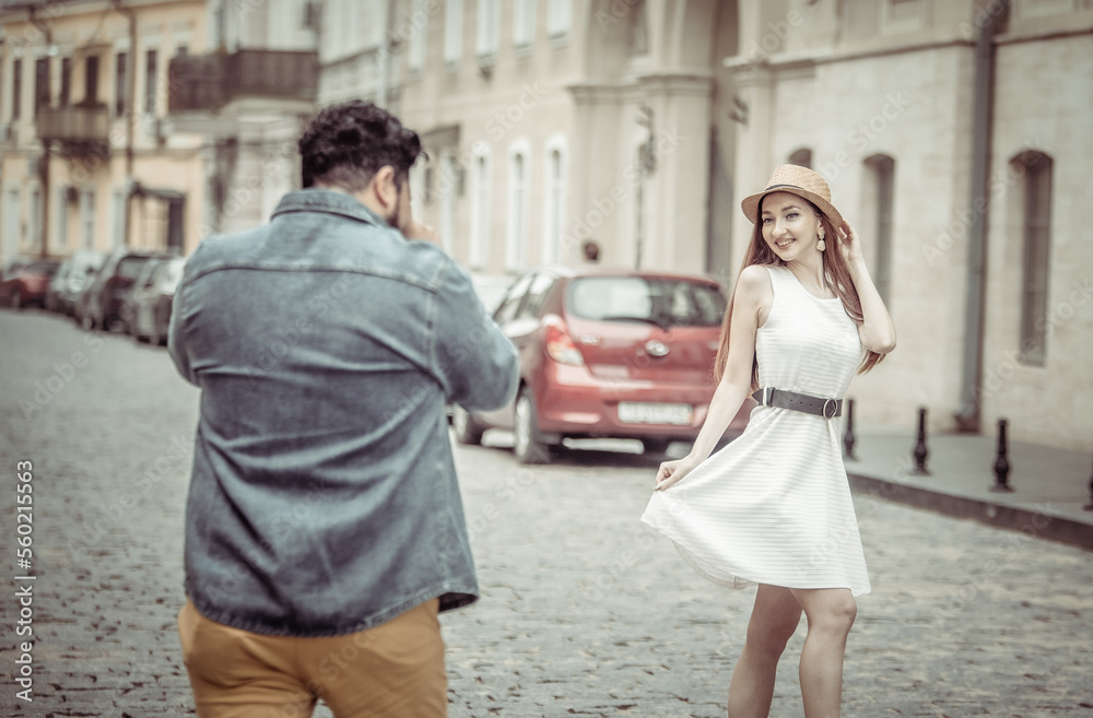 Hispanic man photographs woman on European street. Tourism, travel concept Hispanic man photographs woman on European street. Tourism, travel concept