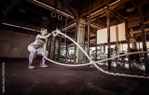 Fitness model trains intensely with battle ropes in the gym. Functional training