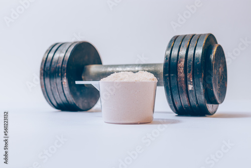 Whey protein powder in a scoop next to rusty dumbbell