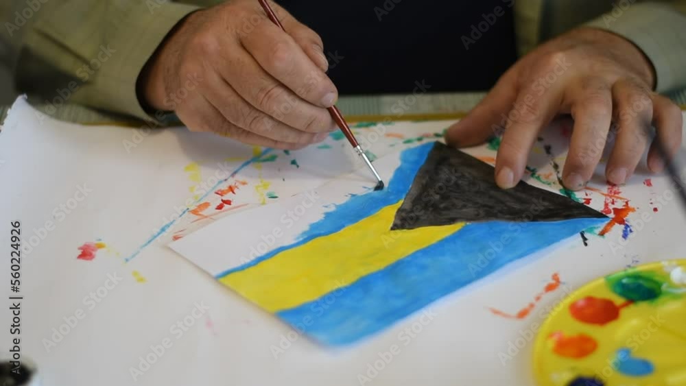Male hands with a brush and paints draw the flag of the Bahamas. Male hands with a brush and paints draw the flag of the Bahamas.