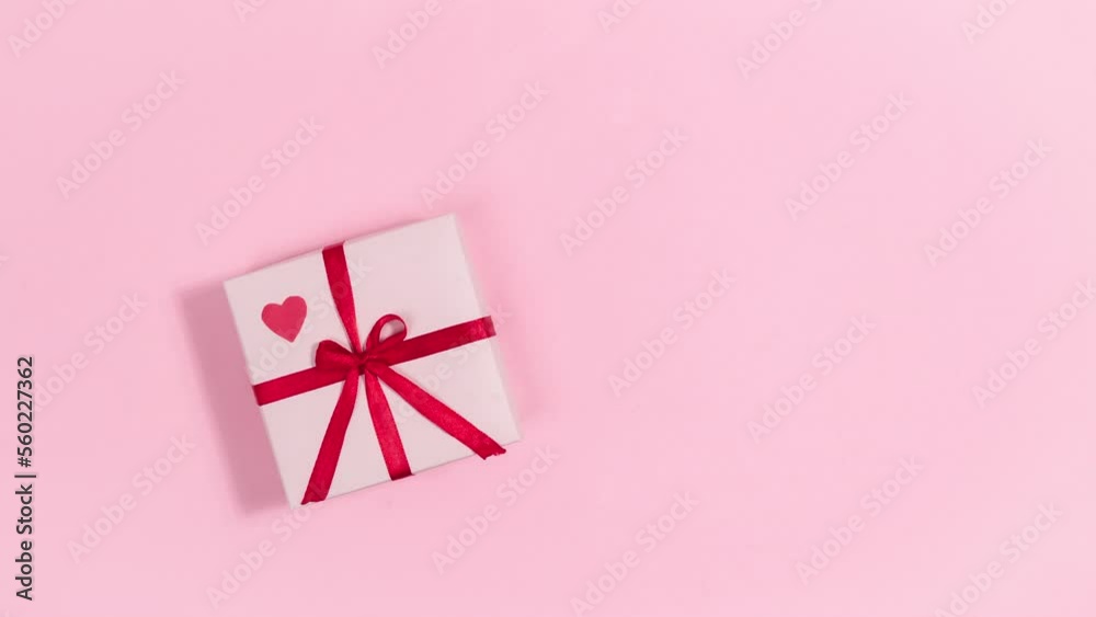 4k Red heart beats on pink gift box tied with a red ribbon. Greeting card for valentine's day. Pink background. Copy space. Flat lay. Looped stop motion animation. 4k Red heart beats on pink gift box tied with a red ribbon. Greeting card for valentine's day. Pink background. Copy space. Flat lay. Looped stop motion animation.