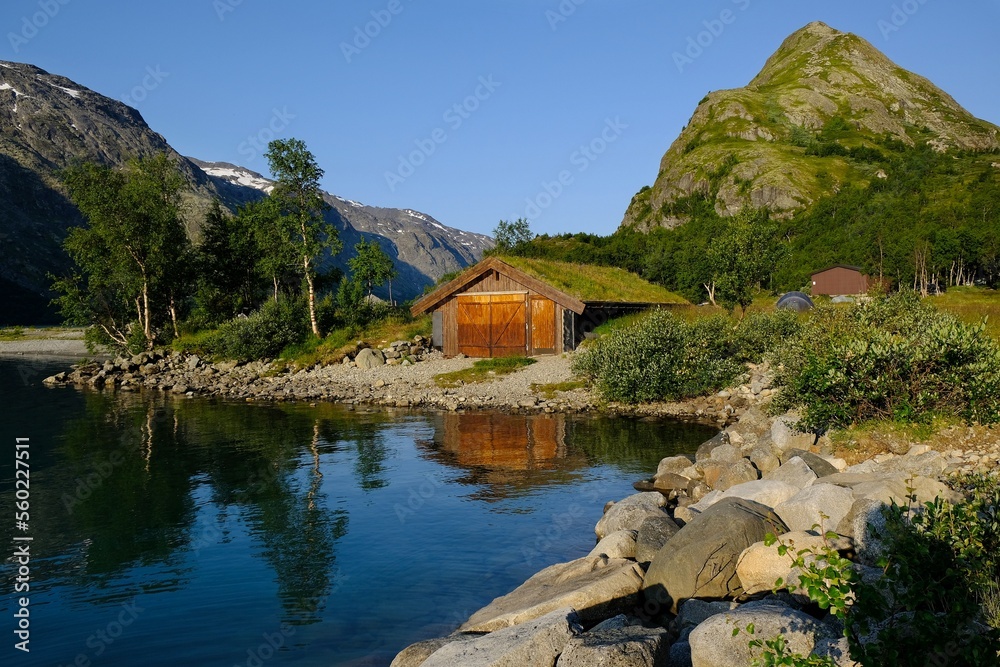Wooden house by lake. Beautiful surroundings of a mountain hut on Lake Gjende in Norway, below the world-famous Besseggen mountain ridge.