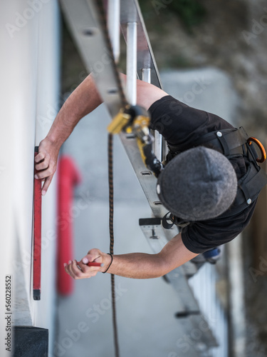 Fototapeta Naklejka Na Ścianę i Meble -  an electrical engineer of the team installs the electrical cables for the autonomous photovoltaic solar panel system. It is installed on a scale and uses a meter and a pencil for position measurements