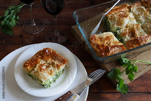 Cucina greca tradizionale. Spanakopita, un pezzo di torta di pasta fillo greca con ripieno di formaggio feta e spinaci su piatto bianco.