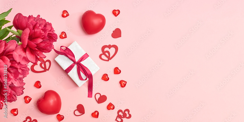 Flat lay valentines day frame with red peonies and red hearts, gift box on a pink background. Valentines day banner with copy space Flat lay valentines day frame with red peonies and red hearts, gift box on a pink background. Valentines day banner with copy space