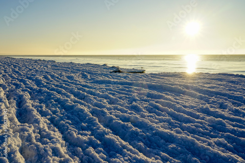 Winter sunset by the Baltic Sea, water waves gradually turning into ice waves due to strong frost