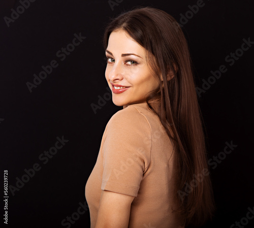 Beautiful young business toothy smiling woman thinking and looking happy with long healthy hair on dark black background with empty copy space. Portrait