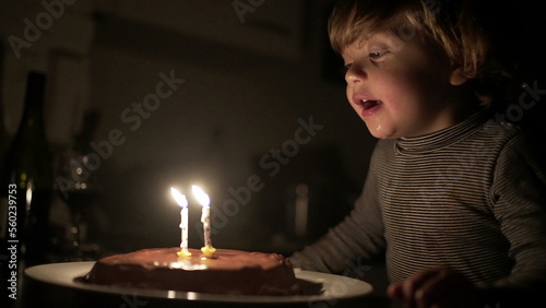 Cute child blowing birthday candles. Toddler boy celebrates anniversary  relighting magic candle