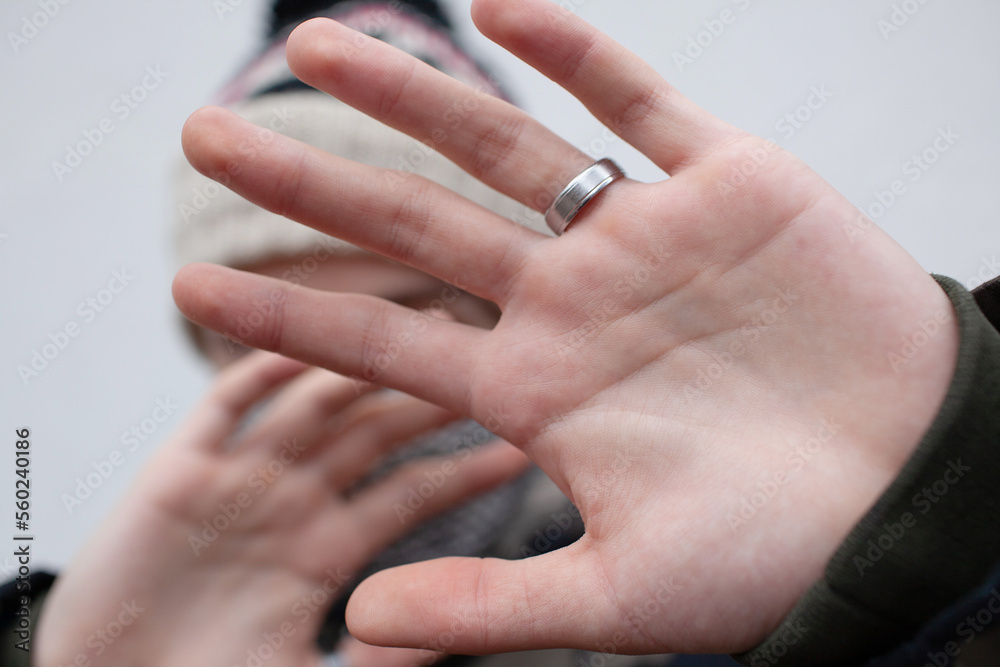 A young guy in a military camouflage protects himself with an open palm