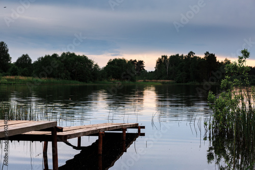 Wooden jetty on the lake at sunset in summer, landscape.