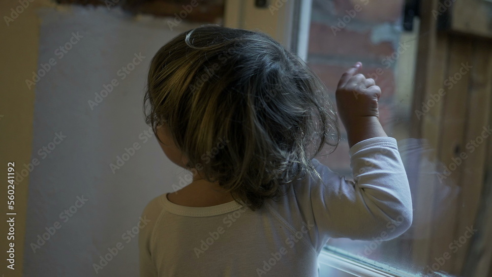 Fototapeta premium Child boy standing by window pointing at something outside