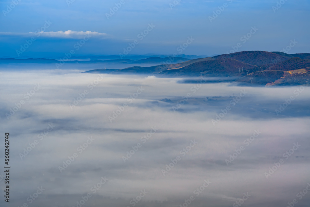 Aerial view of the town in the early morning mist is beautiful in the highlands. Low clouds and fog cover the sleeping city, photo in full moon light. Alpine mountain valley mists landscape at dawn