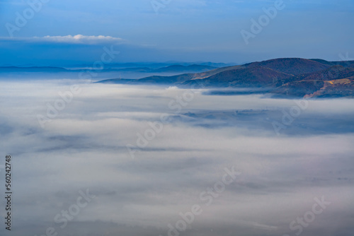 Aerial view of the town in the early morning mist is beautiful in the highlands. Low clouds and fog cover the sleeping city, photo in full moon light. Alpine mountain valley mists landscape at dawn © Creatikon Studio