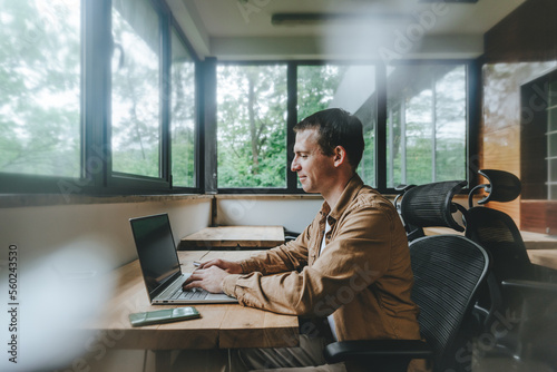 Young businessman working in office looking at laptop