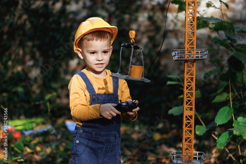 Dreaming of future profession. Little boy builder in uniform working on construction site. Child future engineer builder architect with safety helmets looking on cranes. Dream concept