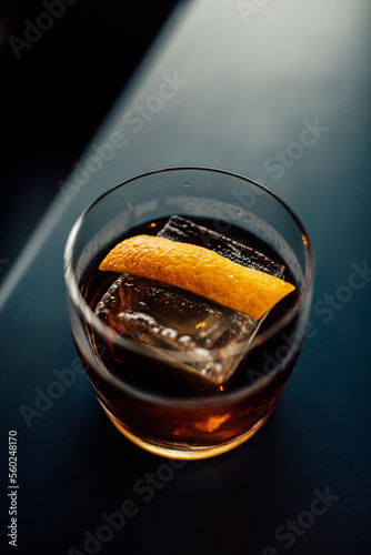 Whiskey cocktail with orange peel garnish and one large ice cube