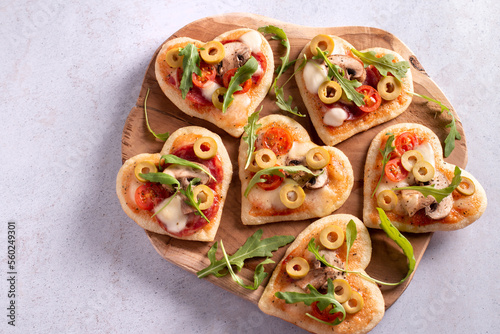 Heart shape mini pizzas on wooden board for Valentines day holiday, top view