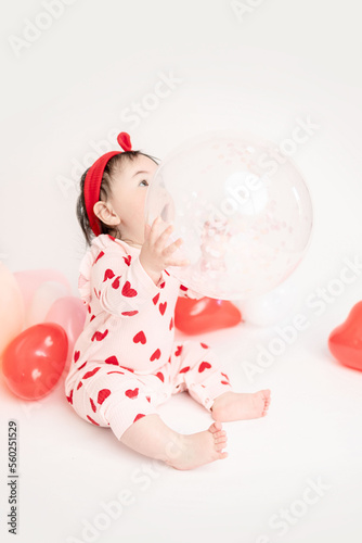 baby with valentine's heart shaped balloons