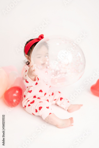 baby with valentine's heart shaped balloons