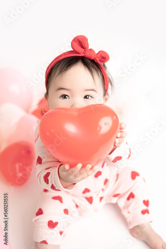 baby with valentine's heart shaped balloons