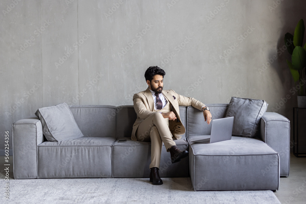 Obraz premium Happy businessman relaxing at home on the couch with a laptop