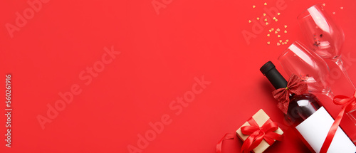 Composition with bottle of wine, glasses and gift for Valentines Day on red background with space for text