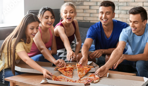 Friends taking slices of hot tasty pizza from cardboard box at home party