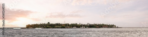 A panoramic view of a stunning dramatic in shades of purple sunset over the pacific sea, in the Maldives islands; tropical warm sunlight around clouds, the water level at the bottom
