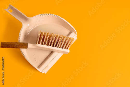 Dustpan and brush on orange background