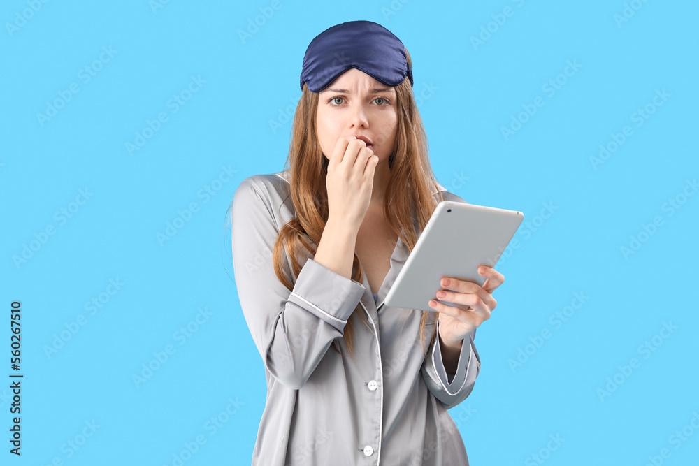 Young woman with tablet computer biting nails on blue background Young woman with tablet computer biting nails on blue background