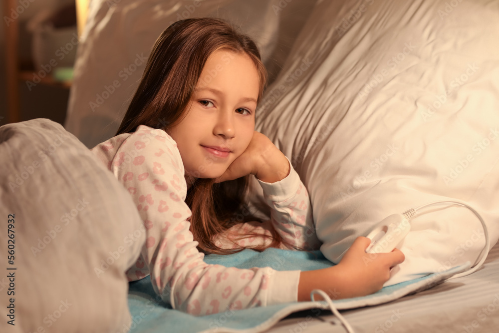Little girl turning on electric heating pad in bedroom at night Little girl turning on electric heating pad in bedroom at night