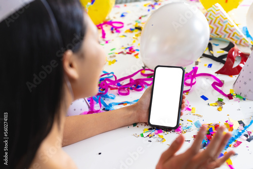 Image of biracial woman using smartphone with copy space on screen having party at home