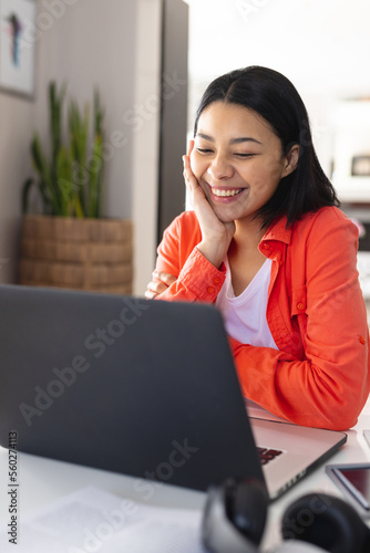 Vertical image of happy biracial woman making video call on laptop smiling at home, copy space