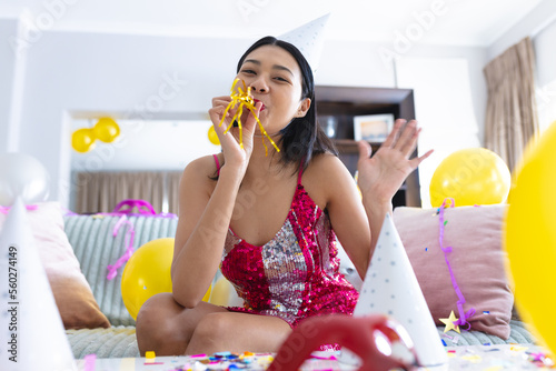 Happy biracial woman having party at home making video call and waving, copy space