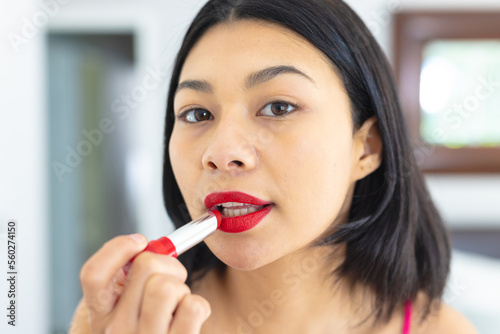 Portrait close up of biracial woman putting on red lipstick, copy space