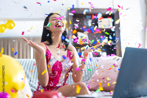 Happy biracial woman having party at home with falling confetti making laptop video call, copy space