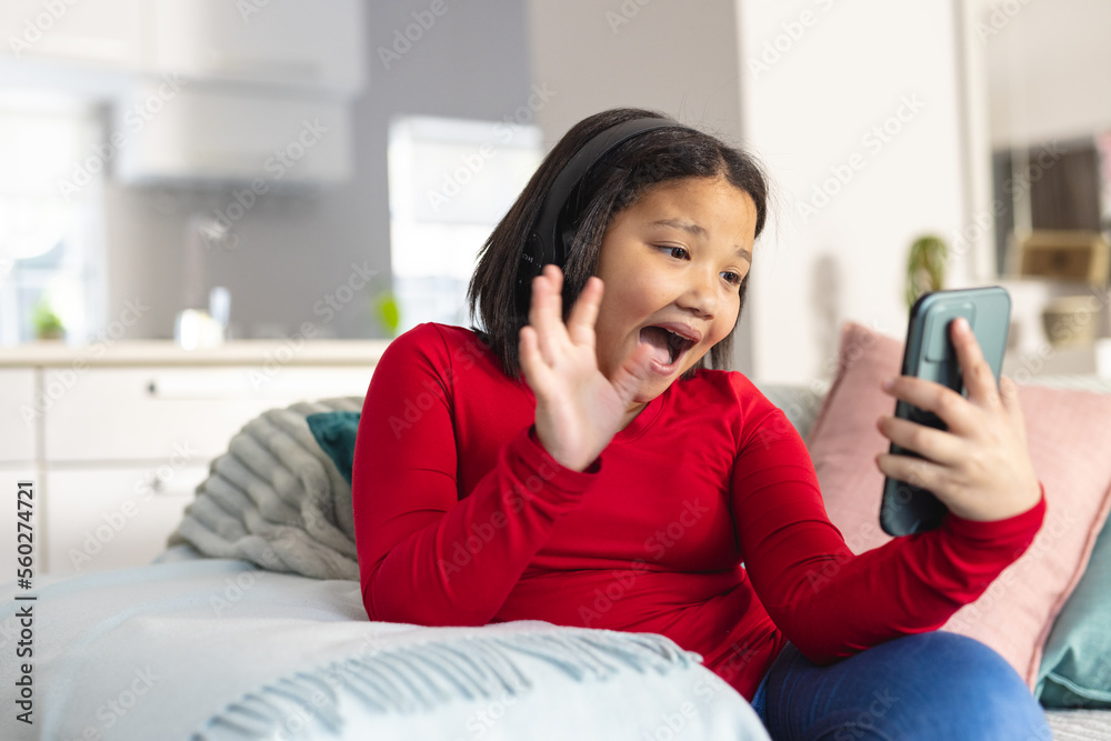 Happy asian girl sitting on sofa in living room and using smartphone Happy asian girl sitting on sofa in living room and using smartphone