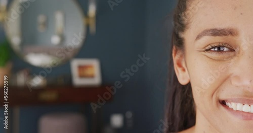 Video half face portrait of happy biracial woman at home, smiling to camera, with copy space photo
