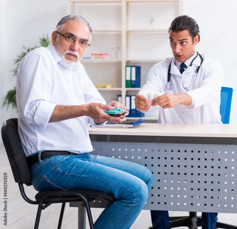 Fototapeta premium Old man visiting young male doctor