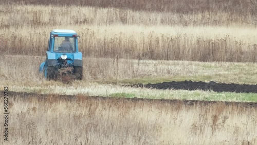 Tractor plowing agriculural farm field preparing soil for seeding photo