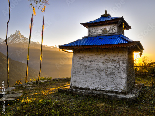 A little religious shrine building sits on a grassy terrace in front of a mountain in the Annapurna region of Nepal. photo