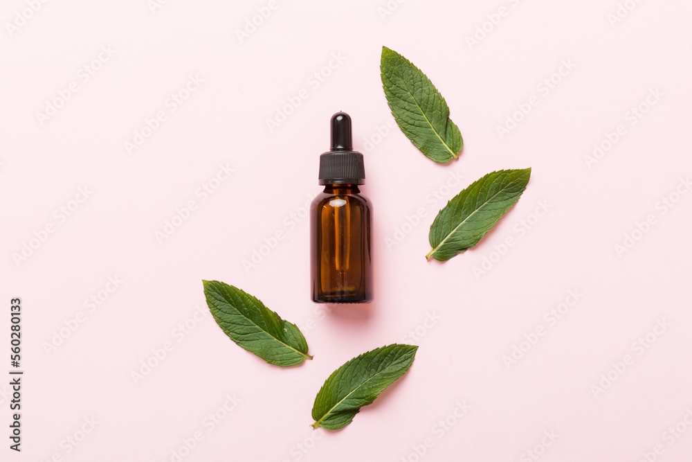 Natural Mint Essential Oil in a Glass Bottle. organic cosmetics with herbal extracts of mint on colored background Natural Mint Essential Oil in a Glass Bottle. organic cosmetics with herbal extracts of mint on colored background