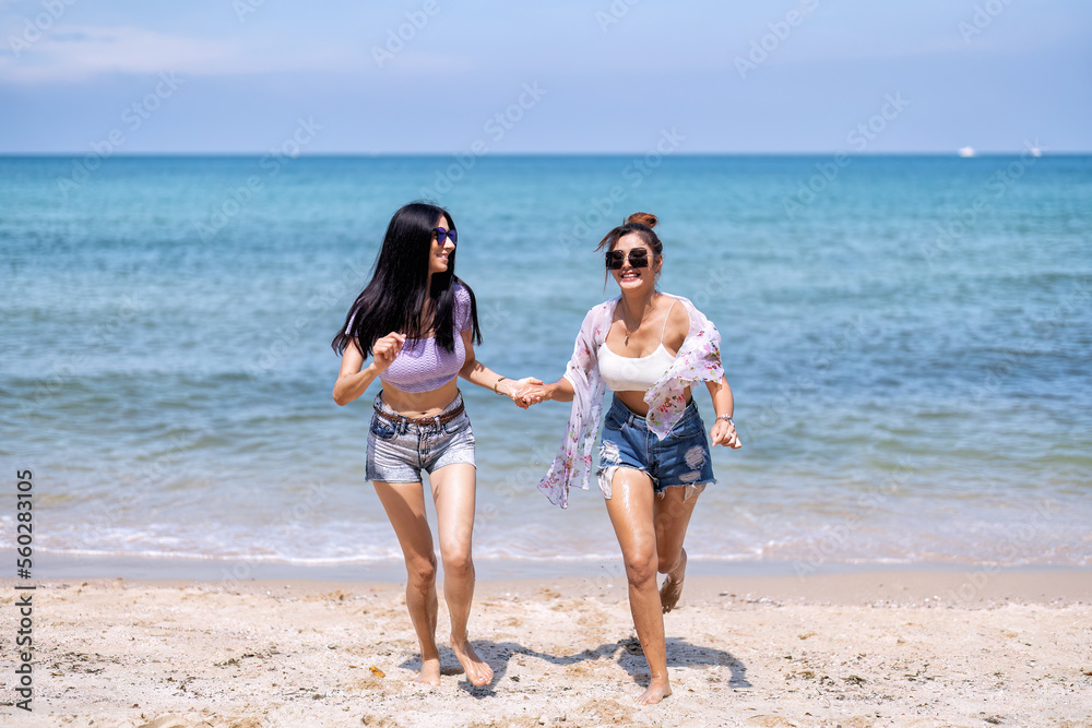 Couple LGBTQ girl on holiday happy running playing dancing along the beach on love emotion