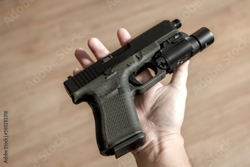Fotografija Pistol handgun with attachment on the palm of a man soldier