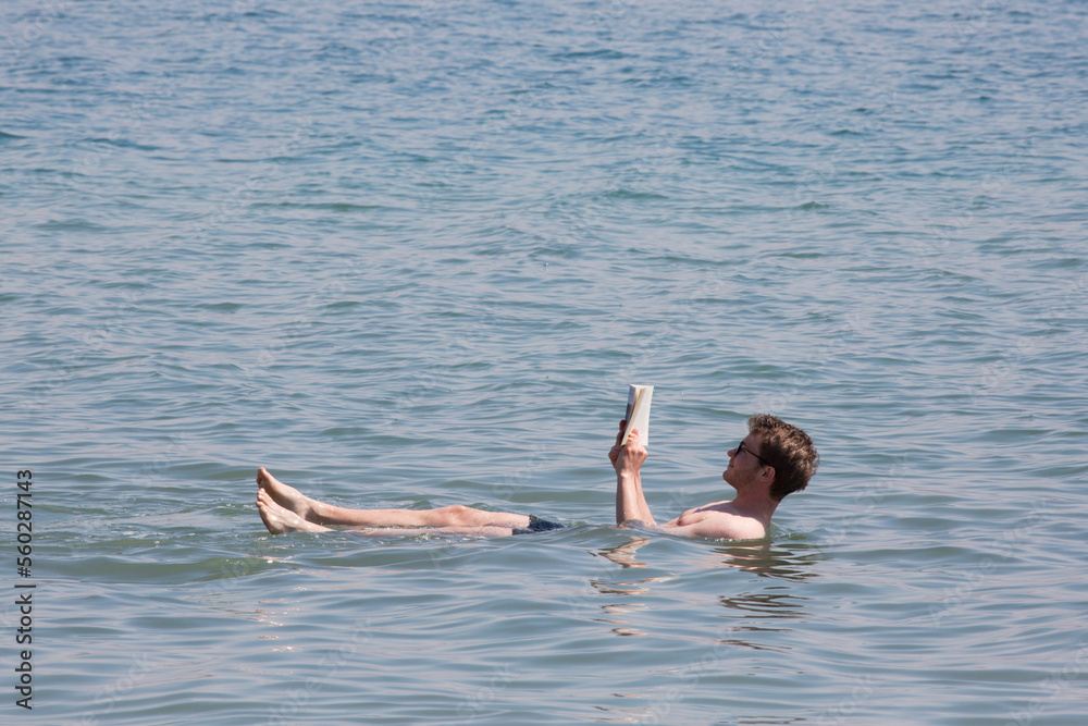 Junger Mann liest - liegend im Toten Meer - ein Buch