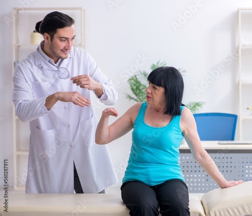 Young male doctor examining old female patient